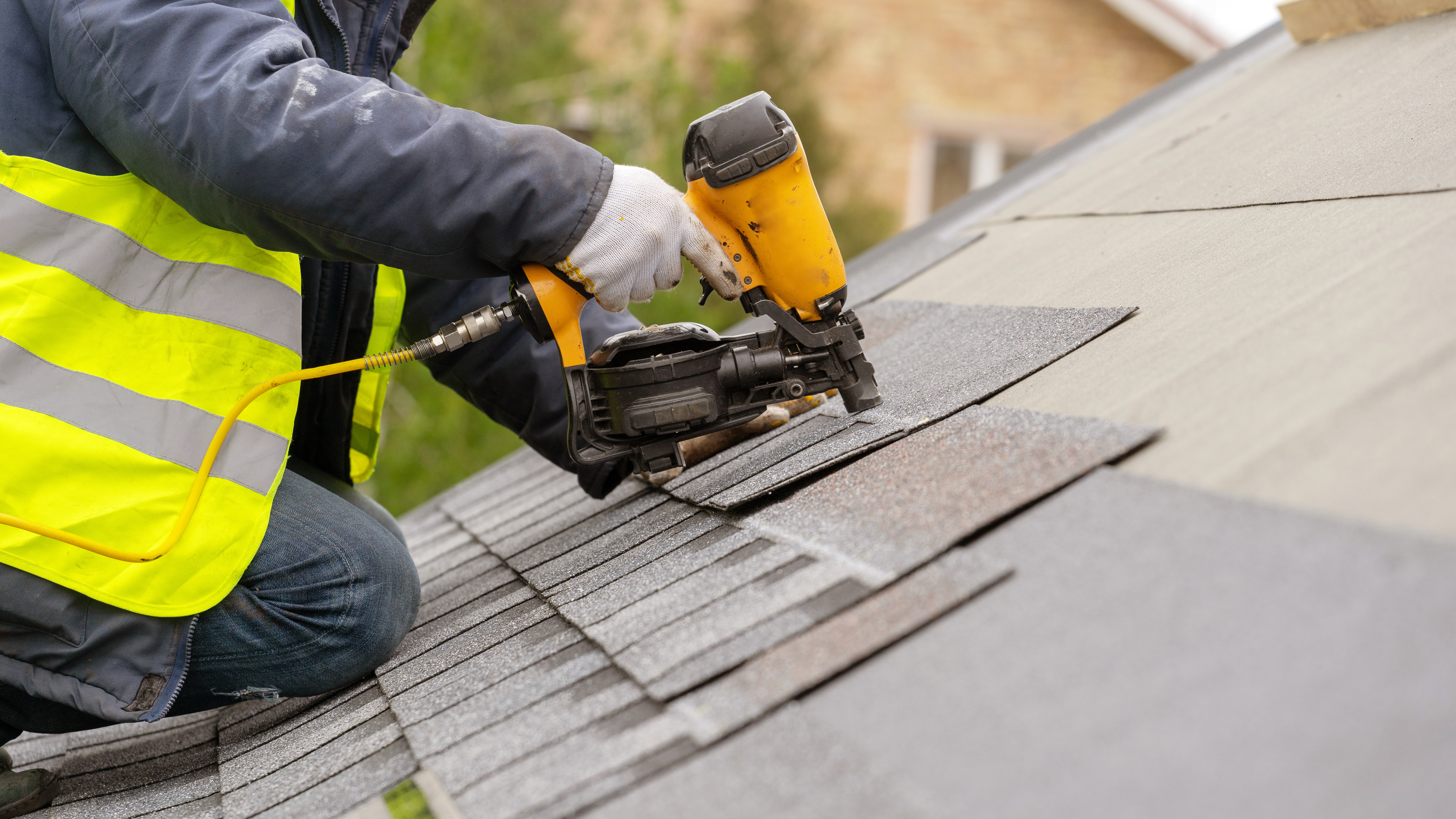 Worker installing shingles on roof