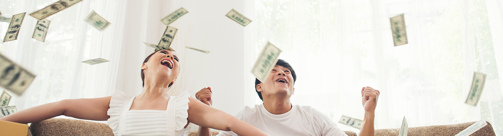 two people looking at money coming from the ceiling of their house.