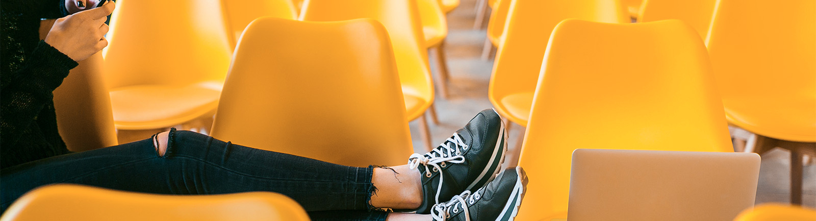 a person laying on a group of yellow chairs with black sneakers.