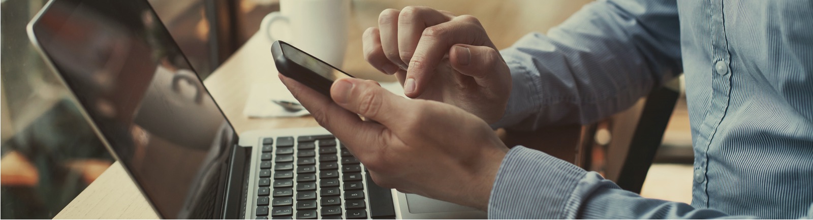 a person using their mobile phone in front of their laptop